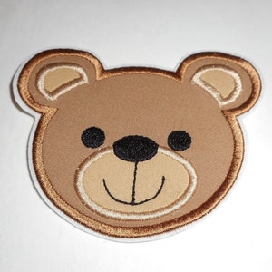 May include: Brown embroidered iron-on patch of a teddy bear face with black eyes and nose.