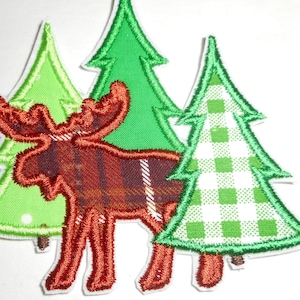 May include: Embroidered patch featuring a moose with a plaid pattern in shades of red and brown, set against a backdrop of three green Christmas trees. The trees have white and green gingham and solid green patterns.