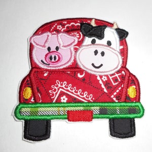 May include: Red truck with a green plaid bed, carrying a pink pig and a black and white cow. The truck has a red and white bandana pattern on the sides.