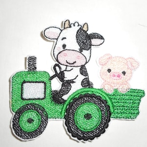 May include: An embroidered iron-on patch featuring a green tractor with black wheels and a white window. A black and white cow sits in the driver seat holding the steering wheel, while a small pink pig sits in the back of the green trailer.