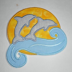 May include: A blue and white embroidered patch with two dolphins jumping over a wave in front of a yellow sun.
