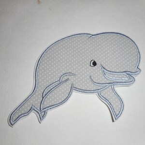 May include: A white embroidered patch of a dolphin with a blue outline. The dolphin is swimming with its mouth open and has a black eye.
