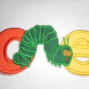 May include: An embroidered patch featuring a green caterpillar positioned between a large orange letter C and a yellow letter E. The caterpillar has a segmented body, small antennae, and two orange eyes. The letters and caterpillar have white borders.