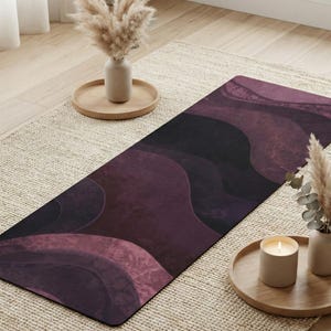May include: A yoga mat with a dark purple and black abstract design. The mat features a wavy pattern in shades of purple and black. The mat is on a beige rug, with decorative items in the background.