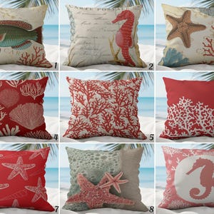 May include: A selection of decorative cushions featuring marine life and coastal designs. The cushions display images of fish, seahorses, starfish, and coral in red, beige, and blue hues. They are square-shaped and made of fabric.