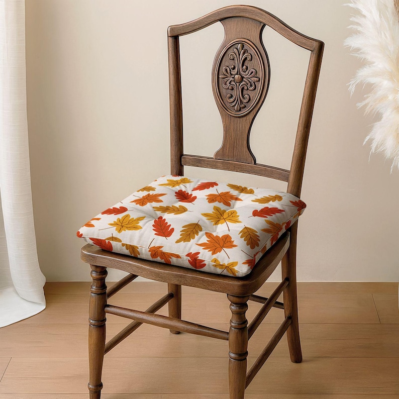 A wooden chair with a decorative backrest and a cushion featuring a leaf pattern is placed on a wooden floor.