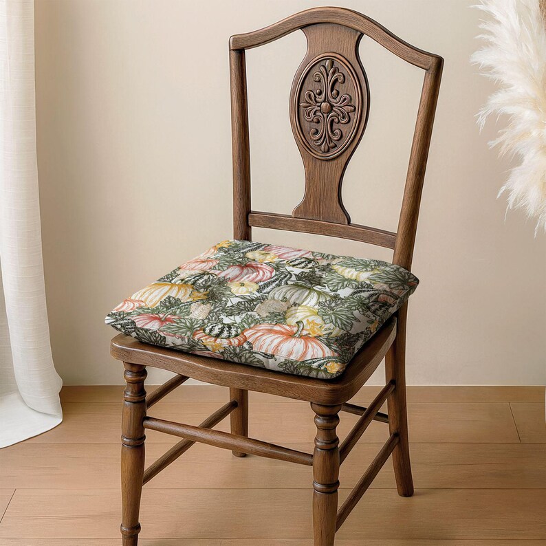 A wooden chair with a floral patterned cushion on the seat, placed on a wooden floor against a white wall.