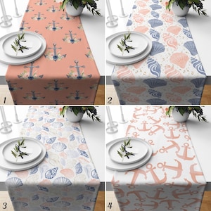 May include: A collection of four table runners featuring nautical patterns. Option one has navy anchors with floral accents on a peach background. Option two displays blue and peach seashells on white. Option three shows blue and peach shells on white. Option four features peach anchors on white.