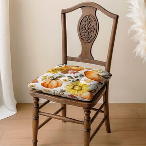 A wooden chair with a decorative backrest and a floral patterned seat cushion.