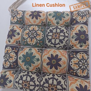 a square cushion with a floral pattern in shades of blue, green, and orange. The cushion appears to be made of a soft, plush material.