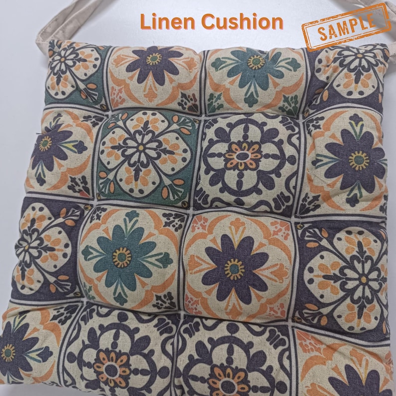 a square cushion with a floral pattern in shades of blue, green, and orange. The cushion appears to be made of a soft, plush material.
