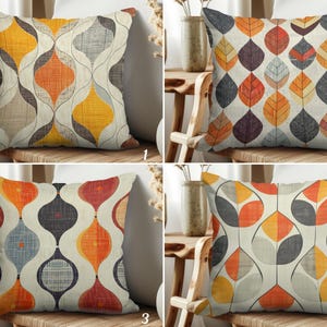 May include: Four decorative cushions with geometric patterns. Cushions feature designs with orange, yellow, grey, and red shapes on a cream background. Each cushion is square and rests on a wooden chair.