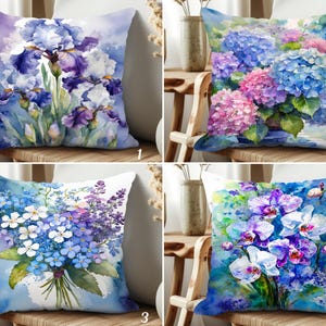 May include: Four decorative throw pillows with watercolor floral designs. The pillows feature irises, hydrangeas, a bouquet of blue and white flowers, and orchids in shades of blue, purple, and pink. The pillows are square and placed on wooden chairs.
