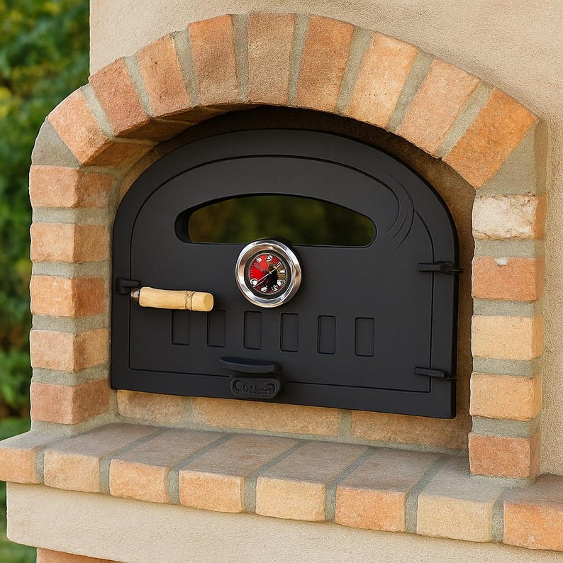Puede incluir: Un horno de pizza negro para exteriores con un arco de ladrillo. La puerta del horno tiene un term&oacute;metro y un mango de madera. La alba&ntilde;iler&iacute;a es una mezcla de ladrillos rojos y beige, creando una est&eacute;tica r&uacute;stica.