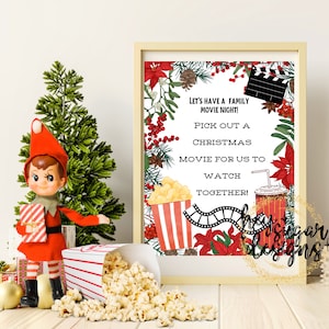 May include: A printable sign with a Christmas movie night theme. The sign features a red and white striped popcorn bucket, a red and white striped cup with a straw, a film reel, and a red clapperboard. The sign has the text "Let's have a family movie night! Pick out a Christmas movie for us to watch together!"