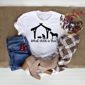 May include: White t-shirt with a black silhouette of a nativity scene and the text "What child is this?"