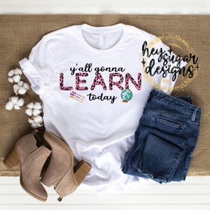 May include: White t-shirt with a pink and black leopard print design that says "y'all gonna LEARN today" with a globe icon.