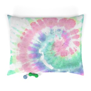 May include: A tie-dye patterned dog bed with a green and blue dog toy and a blue ball.