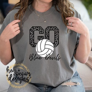 May include: Gray t-shirt with a black and white volleyball graphic and the text "GO Blue Devils" in a leopard print font.