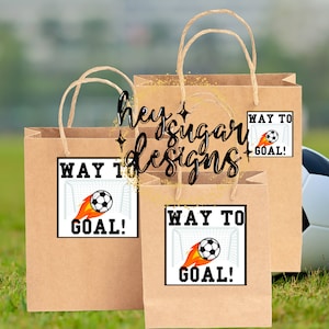 May include: Three brown paper gift bags with handles. Each bag has a white square sticker with a soccer ball, flames, and a goal net. The text on the sticker says "Way to Goal!"