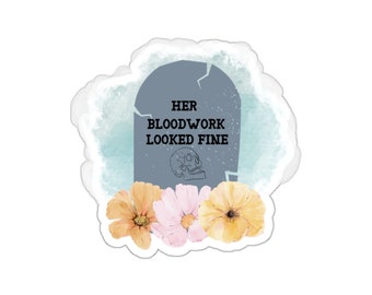 May include: A sticker with a tombstone design featuring the text "HER BLOODWORK LOOKED FINE" and a skull illustration. The tombstone is surrounded by watercolor flowers in shades of yellow, pink, and orange.