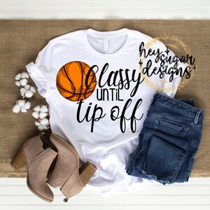 May include: White t-shirt with a basketball graphic and the text "Classy Until Tip Off".