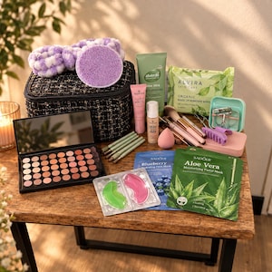 May include: A black tweed makeup bag with a purple headband and sponge, a brown eyeshadow palette, various makeup brushes, a tube of Alverde cream, Essence foundation, Alvira makeup wipes, a lash curler, and Sadoer face masks.