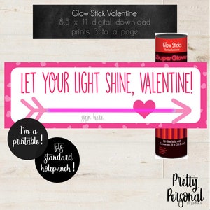 May include: A Valentine's Day printable sign with the text "LET YOUR LIGHT SHINE, VALENTINE!" in pink, featuring an arrow design. Includes a black circle that says "I'm a printable!" and another that says "fits standard holepunch!"