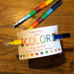 May include: A Valentine's Day card with the words "Valentine, you color my world!" and a rainbow of hearts. Two colorful pens are inserted into the card. The pens are segmented in rainbow colors.
