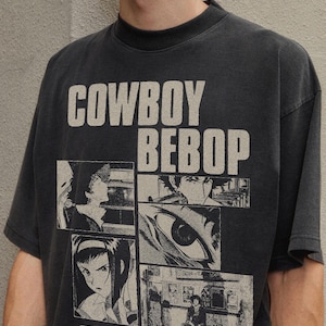 以下が含まれることがあります： 大胆なオフホワイトのフォントで「COWBOY BEBOP」と書かれた濃いグレーのTシャツ。テキストの下には、アニメシリーズのシーンを描いた4つの白黒パネルがあります。シャツには「OH WELL WHATEVER HAPPENS, HAPPENS」というテキストも含まれています。