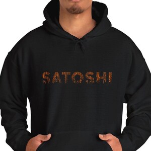 Può includere: Felpa con cappuccio nera con la parola "SATOSHI" stampata in arancione sul davanti.