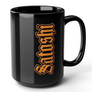 Op de afbeelding: Zwarte keramische mok met een verticale oranje grafische afbeelding met de tekst "Satoshi" in een gotisch lettertype.