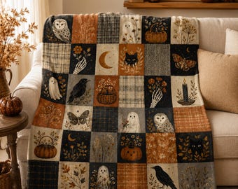 May include: A patchwork throw blanket featuring a grid of squares with illustrations of owls, ghosts, black cats, pumpkins, moths, crows, crescent moons, skeletal hands holding flowers, and botanical patterns in shades of orange, black, and cream.
