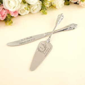 以下が含まれることがあります： 装飾的なハンドルが付いたシルバーのケーキナイフとサーバーのセット。ナイフとサーバーには「Stu & Chanelle」の名前と「2025年9月18日」の日付が刻印されています。サーバーには「S C」のイニシャルが入った花の模様があります。