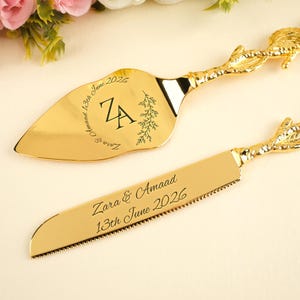 以下が含まれることがあります： 金色のケーキサーバーとナイフのセット。 サーバーは葉のようなハンドルで、ナイフには「Zara & Amaad 13th June 2026」の文字が刻まれています。 サーバーには「ZA」のイニシャルと「13th June 2026」の日付も記載されています。