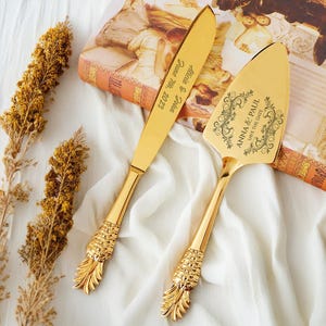 以下が含まれることがあります： 金色のパイナップル型のケーキサーバーセットで、彫刻されたテキストが施されています。サーバーには「Anna & Paul Save the Date」というテキストが、ナイフには「Anna & Paul June the 20th 2023」というテキストが刻まれています。