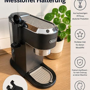 Può includere: Una macchina da caffè espresso De'Longhi Dedica nera con parte superiore e dettagli argentati. L'immagine include un supporto per misurino stampato in 3D e il testo "3D Druck Messlöffel Halterung".