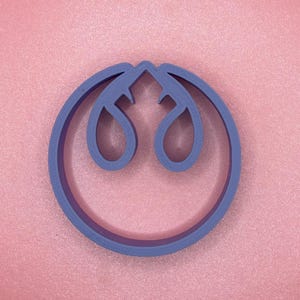 Może przedstawiać: Fioletowa plastikowa foremka do ciasteczek w kształcie symbolu Rebelii z Gwiezdnych Wojen.