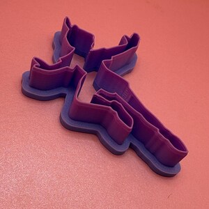 May include: Purple plastic cookie cutter shaped like a person doing a handstand.