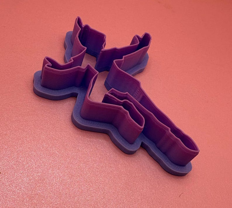 May include: Purple plastic cookie cutter shaped like a person doing a handstand.