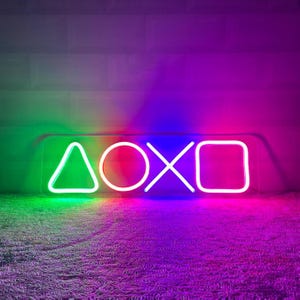 Pode incluir: Um letreiro de néon com os símbolos do controlador PlayStation: um triângulo, um círculo, uma cruz e um quadrado. Os símbolos são iluminados em verde, rosa, azul e vermelho, respectivamente.