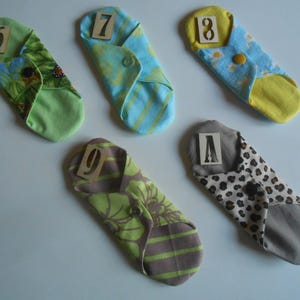 May include: Five cloth pads with different patterns and numbers 6, 7, 8, 9, and A printed on them.