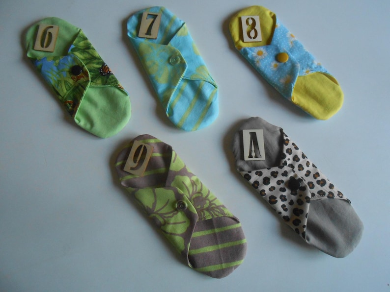 May include: Five cloth pads with different patterns and numbers 6, 7, 8, 9, and A printed on them.