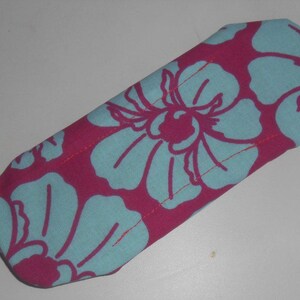 May include: A pink fabric pouch with a blue floral pattern. The pouch is sewn with a light pink thread.
