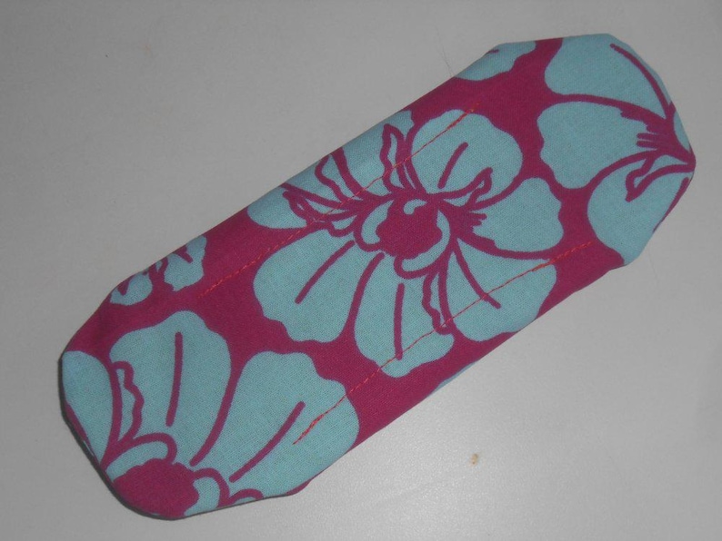 May include: A pink fabric pouch with a blue floral pattern. The pouch is sewn with a light pink thread.
