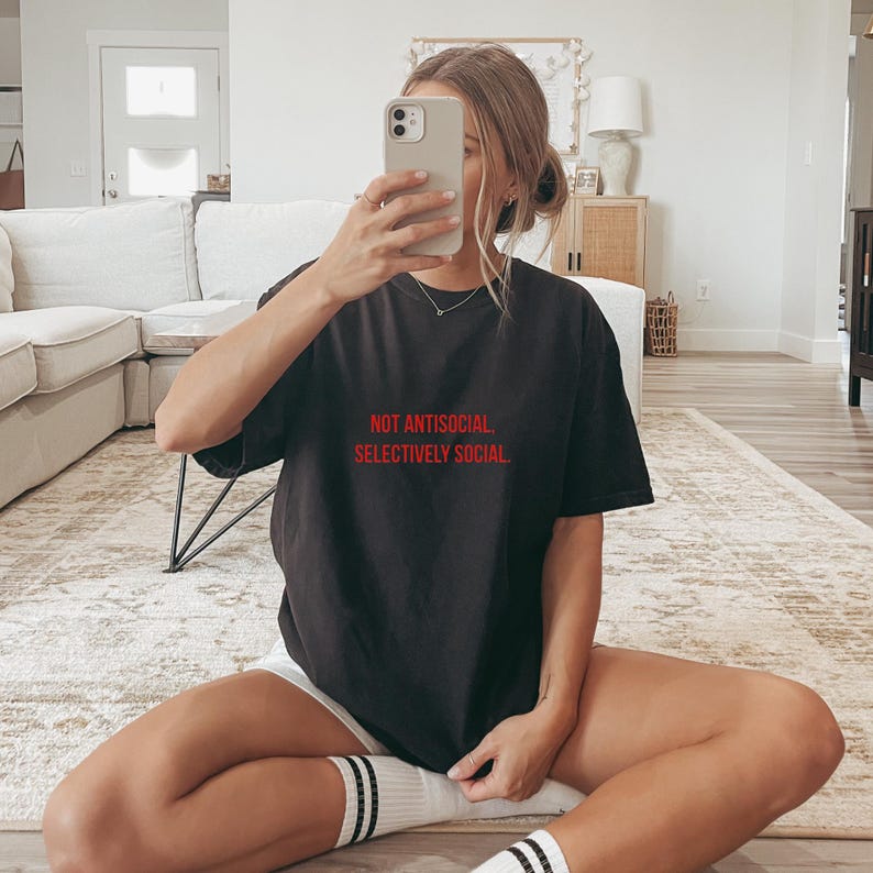 May include: A black t-shirt with the text "NOT ANTISOCIAL. SELECTIVELY SOCIAL." in red lettering.
