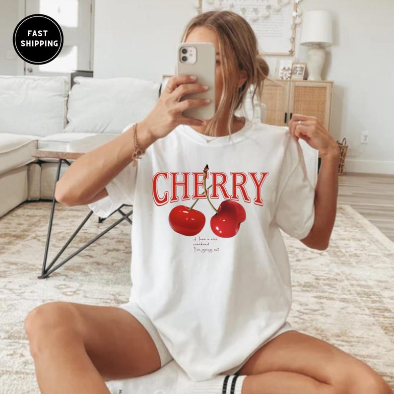 May include: White t-shirt with a red cherry graphic and the text "CHERRY" in red. The text below the cherries reads "If I have a nice soundtrack I'm going out."