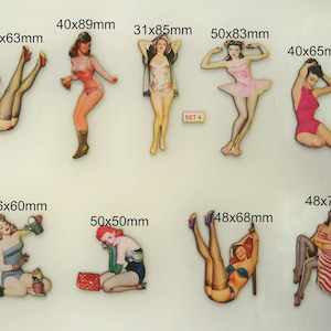 May include: Set of ten wood cutouts featuring pin-up style illustrations of women in various poses. The cutouts are painted in bright colors and have a vintage aesthetic. The cutouts range in size from 31x85mm to 50x83mm.