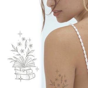 Può includere: Un disegno di tatuaggio a linea di una pila di libri con fiori che crescono dal libro superiore. Il disegno è circondato da piccole stelle.