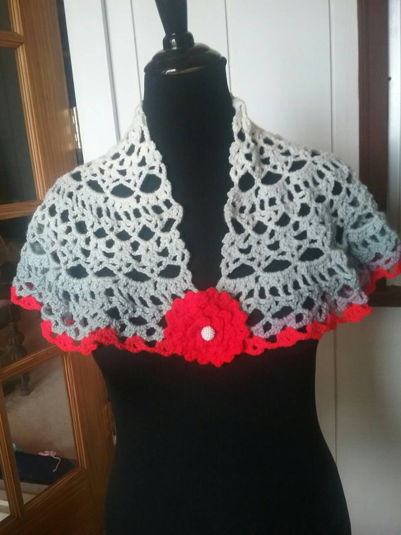 Shawl trimmed in red two fasteners pins one red one blue crocheted by hand.